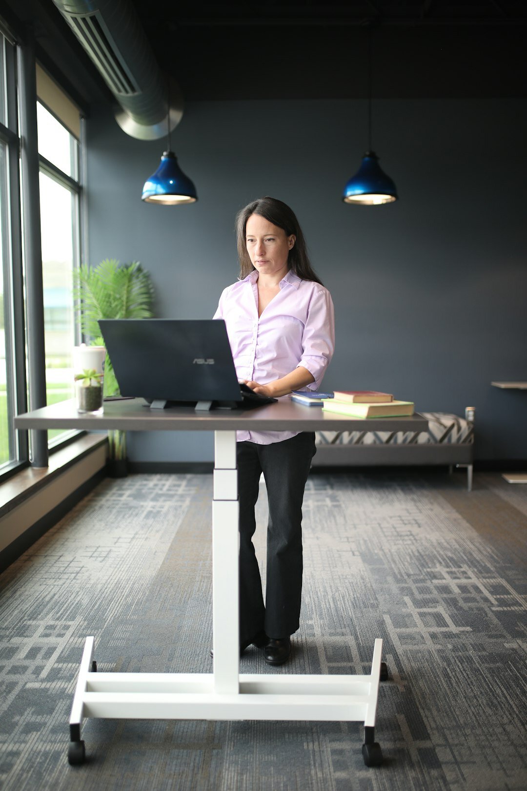 Professional woman writing notes while working on a laptop at a desk